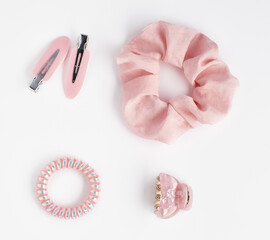 Collection of trendy pink silk elastic band scrunchies and hair clips on white background. Diy accessories and hairstyles concept