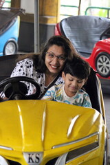 Indian Mom and son is having wonderful time while enjoying car fight ride at an amusement park....