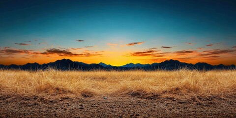 Obraz premium Serene Landscape with Golden Grass and Majestic Mountains Under Vibrant Sunset Sky