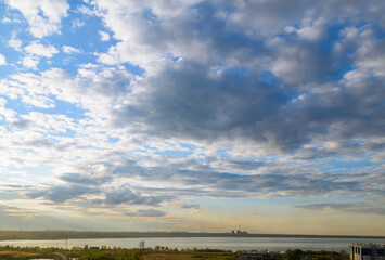 CHP and other plants stand on the shore of the lake in the evening under clouds in the sky
