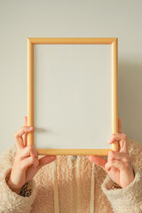 Young woman holding blank frame with copy space against white background. Concept of message of New Year's resolutions, goals, hopes, etc.