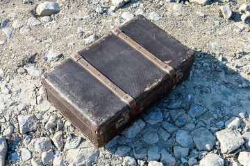 An old worn suitcase on the gravel