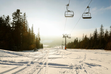 Obraz premium Ski slope in a mountain village and chairlift in winter.