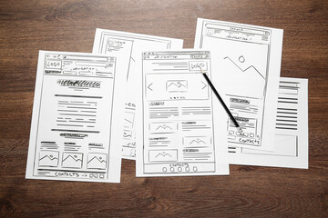 Developing UI design. Sketches of website wireframes and pencil on wooden table, top view