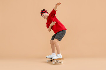 Little boy with skateboard on beige background