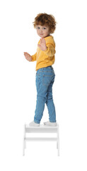 Little boy standing on step stool against white background
