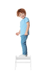 Little boy standing on step stool against white background