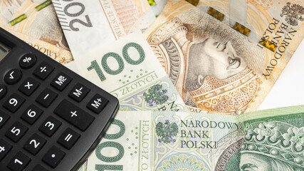 Scattered Polish banknotes and a calculator on them