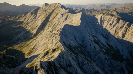 Fototapeta premium Majestic mountain range at sunset, showcasing rugged peaks and deep valleys.