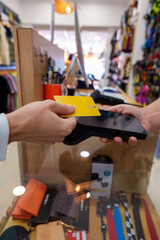 Customer making a contactless payment with a credit card using NFC technology on a POS terminal in a clothing store