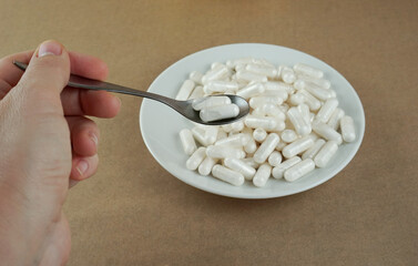 Female hand holding a spoon with white vitamins