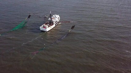 Low aerial view of shrimp boat pulling nets along the South Carolina coast.