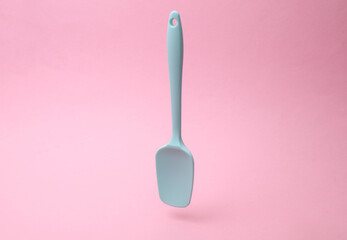 Silicone kitchen spatula floating on a pink background