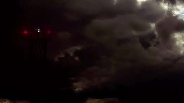 Storm Quickly Approaching to Airport. Communication tower with a rotating antenna and flashing signal lights against the background of rapidly changing weather at dusk