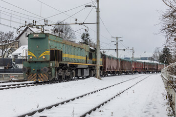 Obraz premium Diesel electric freight train with american style locomotive and open cars or gondolas in snowy wintery environment at ljubljana, slovenia..