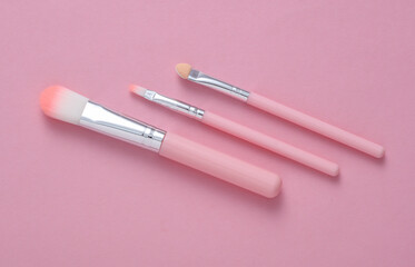 Set of makeup brushes on pink background