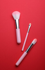 Pink Makeup brushes on red background