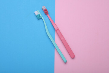 Plastic toothbrushes on blue pink background