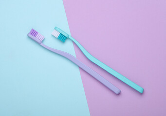 Plastic toothbrushes on a pastel background
