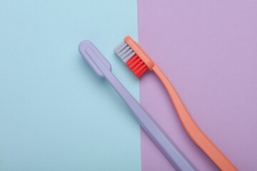 Plastic toothbrushes on pastel background. Top view