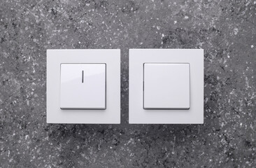 Two Light Switches on a Grey Concrete Background
