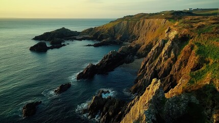 Obraz premium Scenic coastal cliffs at sunset, showcasing rugged terrain and serene waters.