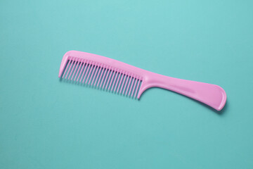 Pink plastic comb on mint green background.