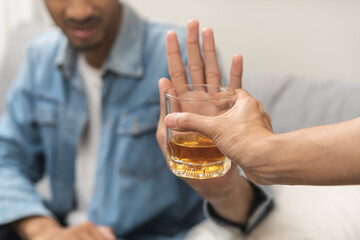 Alcoholism, depressed asian young man refuse, push out alcoholic beverage glass, drink whiskey, sitting alone at night. Treatment of alcohol addiction, having suffer abuse problem alcoholism concept.