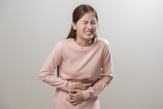 Flatulence asian young woman intolerance hand in stomach ache, suffer from food poisoning, abdominal pain and colon problem, gastritis or diarrhoea when at home. Patient belly, abdomen or inflammation