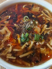 Hot and sour soup garnished with chopped spring onions or scallions