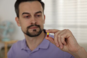 Man with pill at home, selective focus