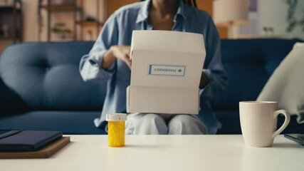 African American female opens a box of pills from a pharmacy delivery service