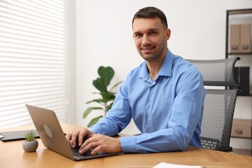 Programmer with laptop at wooden desk indoors