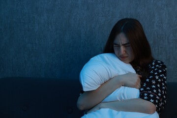 Obraz premium Fear of darkness. Scared young woman hugging pillow on couch indoors at night, space for text