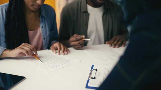 Couple signs healthcare insurance agreements and shakes hands with their agent