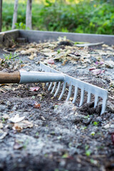 A rake mixing rock dust and compost into soil for sustainable gardening and soil improvement /...