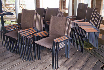 Bunch of wicker plastic chairs outdoors. The cafe is closed, there are no visitors in the early winter morning.