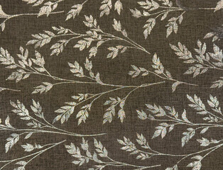 Close up texture of dark brown fabric with gold leaves pattern. Brown linen and golden shiny leaves suitable for table runner or upholstery fabric. Seamless background texture.