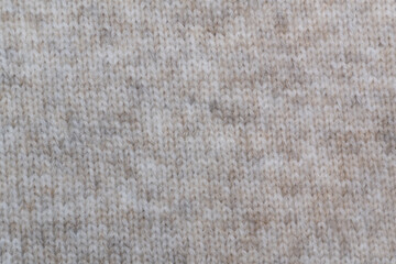 Beige wool knit: The soft texture of beige wool with a visible knit pattern of neat loops. Beige wool fabric: The natural shade adds warmth and coziness, perfect for crafting comfortable clothing.