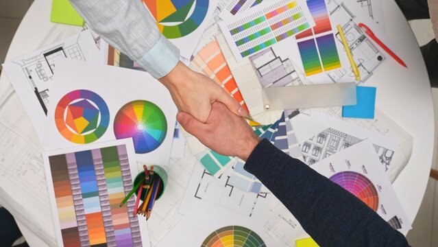 Group of architects, creative interior designers team members meeting in boardroom at desk, discuss design project of new house, close deal shake hands, top view.
