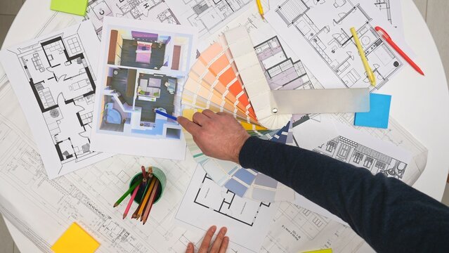Group of architects, creative interior designers and team members meeting in boardroom at desk, discussing design project of new house, choosing palette, top view.