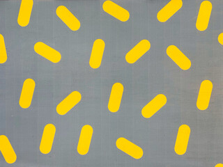 Yellow Ellipse resembling candy scattered randomly with pale blue or grey background. Seamless background texture. 