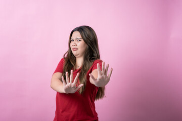 A young woman with long brown hair and light skin, wearing a red T-shirt, makes a disgusted...
