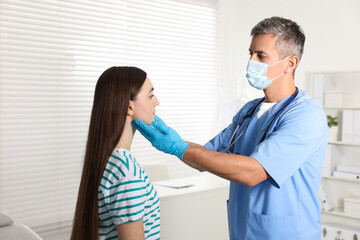 Fototapeta premium Doctor examining woman's throat in clinic during appointment