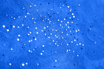 Obraz premium Flying sparks on blue festive background. Abstract festive background of the winner.Classic blue color for your projects