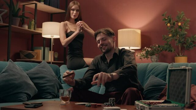 Happy Caucasian elegant playful couple enjoy playing poker cards game lucky rich man male guy winning bet competition stack chips tokens excited woman female girl in dress applauding gambling at home