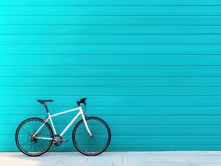 Fototapeta premium A sleek white bicycle rests against a vibrant turquoise wall, showcasing a minimalist and modern aesthetic.