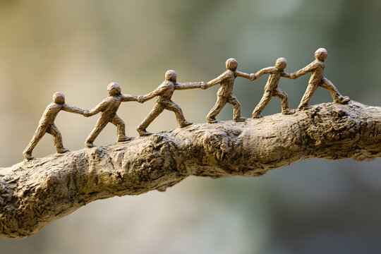 Miniature clay figures holding hands on a branch, symbolizing teamwork, unity, collaboration, and support, representing the strength and balance of working together in harmony