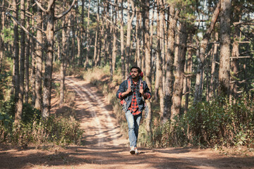 Obraz premium Travelers hiking through a forest with backpacks, exploring the wilderness and taking in the sights of nature as they walk.