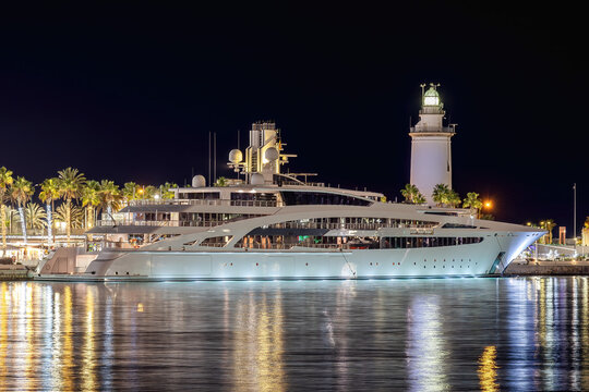 Huge luxury yacht moored in the harbor at night with reflections in the water